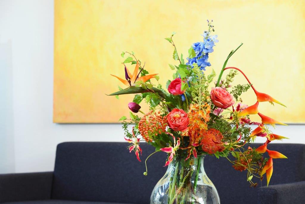 Sfeerdecoratie met zomer bloeiers in een heldere glazen vaas