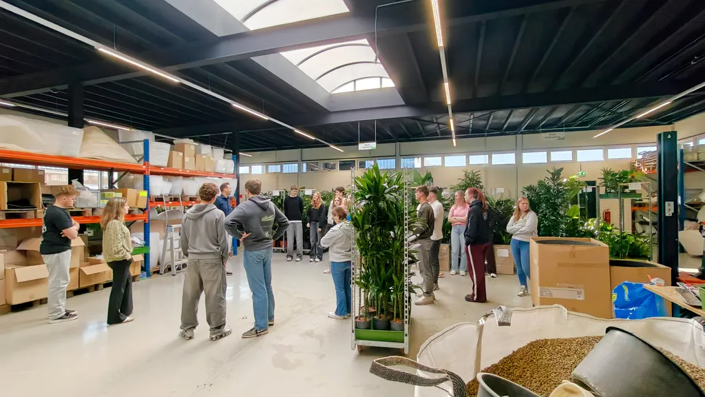 Studenten van de opleiding Groene Retail krijgen een rondleiding door het magazijn van Ten Brinke in Zevenaar, waar de logistiek van grote plantenbakken en substraten centraal staat.