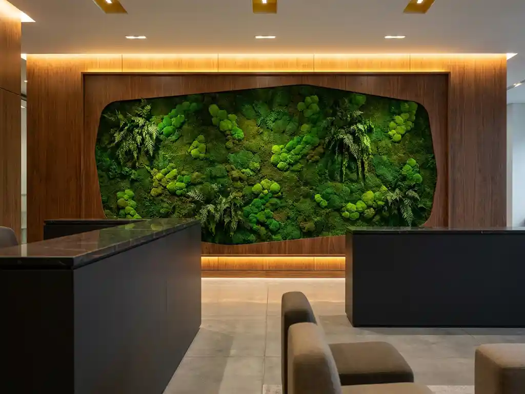 Mosswand met smaragdgroene texturen in een stijlvol kantoorinterieur, verlicht door warm sfeerlicht naast een minimalistische receptiebalie.