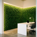 Weelderige smaragdgroene moswand in moderne kantoorhoek met witte bureau en ergonomische stoel onder LED-verlichting