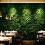 Levendige mosswand in smaragdgroen en bosgroen bedekt achterwand van elegant restaurant met houten tafels en witte tafelkleden