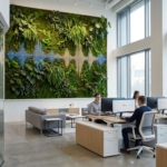 Moderne kantoor met grote groene plantenwand die geluid absorbeert, natuurlijk licht en eigentijds meubilair