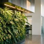 Weelderige verticale plantenwand met LED-groeilampen in moderne kantooromgeving, tropische bladeren tegen witte muur